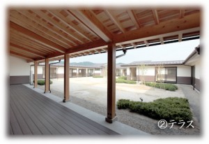 木製の屋根付きテラスから眺める施設の庭園と外構